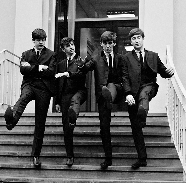 Early Beatles performing on stage in front of a screaming crowd